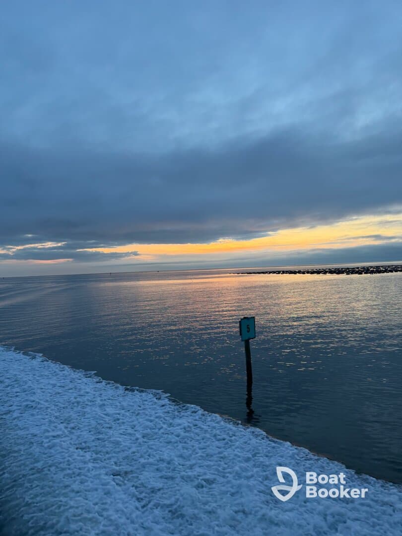 A scenic view of the water at sunset, featuring a marker post, but the image lacks clarity and focus.