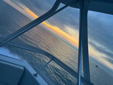A stunning view from the helm of a boat, showcasing a vibrant sunset over calm waters — perfect for evening cruises.