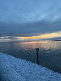 A scenic view of the water at sunset, featuring a marker post, but the image lacks clarity and focus.