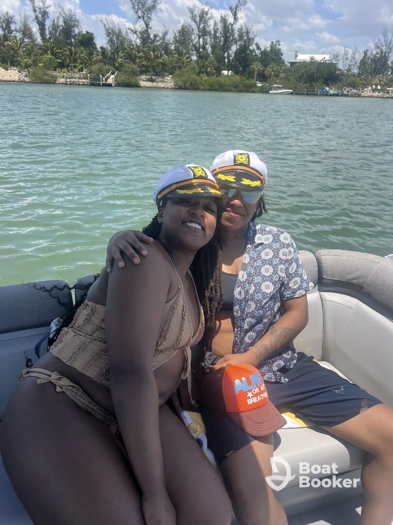 Two friends enjoy a sunny day on the water, sporting captain hats and smiles, perfect for a fun boating adventure.