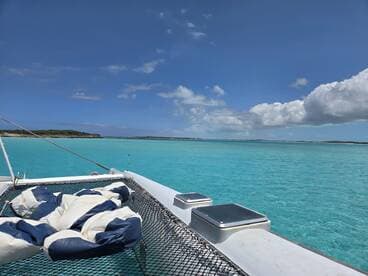 A serene view from the deck of a catamaran, showcasing the stunning turquoise waters and clear skies — perfect for a relaxing day on the water.