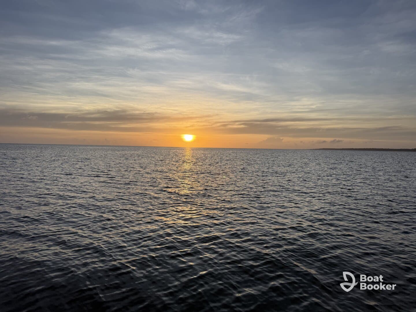 A serene sunset over calm waters, creating a picturesque view perfect for evening boat cruises or relaxation on the water.