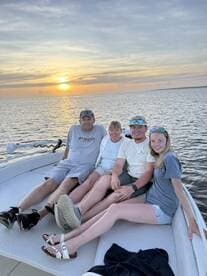 A family enjoys a beautiful sunset together on a boat, capturing a memorable moment on the water.