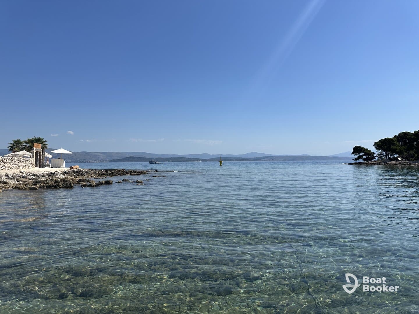 A serene view of a clear coastline with gentle waves and distant islands, perfect for showcasing the beauty of a tranquil day on the water.