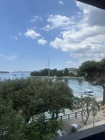 A picturesque view of a harbor with sailboats anchored, framed by lush greenery and a clear blue sky — a perfect representation of a serene coastal getaway.