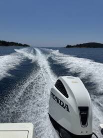 A dynamic view of a Honda outboard motor cutting through the water, showcasing the thrill of speed on a sunny day.