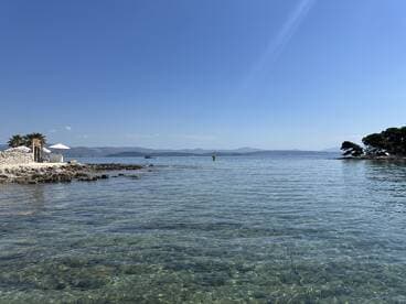 A serene view of a clear coastline with gentle waves and distant islands, perfect for showcasing the beauty of a tranquil day on the water.