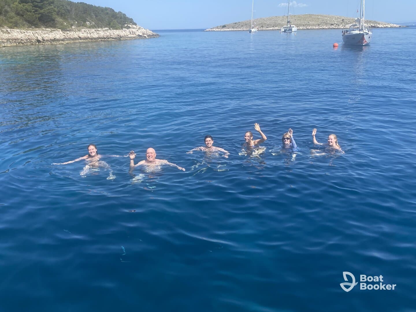 A lively group enjoys a refreshing swim in crystal-clear waters, creating unforgettable memories during their boating adventure.