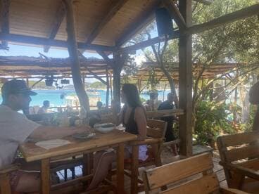 Guests enjoy a meal at a beachside restaurant with stunning views of the turquoise waters, perfect for a relaxing dining experience after a day on the boat.