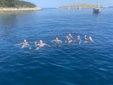 A lively group enjoys a refreshing swim in crystal-clear waters, creating unforgettable memories during their boating adventure.