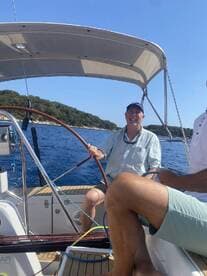 Two friends enjoy a sailing adventure, capturing the joy of being on the water with stunning ocean views in the background.