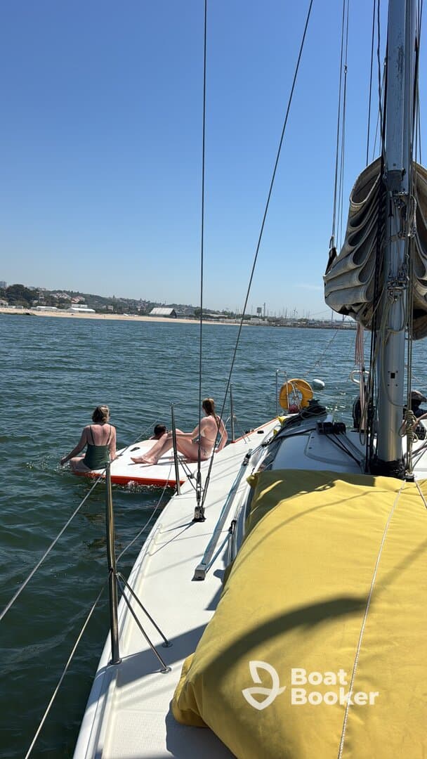A group enjoys a sunny day on the water, with one person paddleboarding and others relaxing on the boat — perfect for summer adventures and fun on the sea.