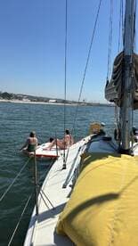 A group enjoys a sunny day on the water, with one person paddleboarding and others relaxing on the boat — perfect for summer adventures and fun on the sea.
