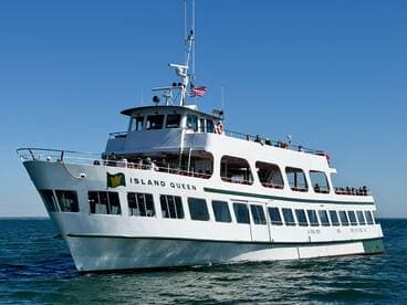 The Island Queen ferry cruises through clear waters, with guests enjoying the scenic views from the deck — a perfect choice for sightseeing adventures.