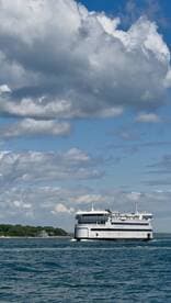 A ferry navigates through calm waters under a picturesque sky, showcasing the beauty of maritime travel.