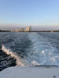 A scenic view from a boat showing the city skyline in the background, with the boat's wake creating a dynamic water effect — perfect for showcasing urban boating experiences.