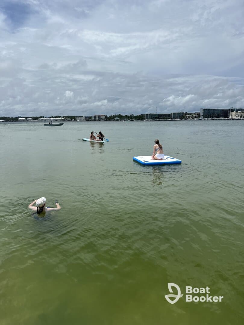 A lively scene featuring friends enjoying paddleboarding and swimming in calm waters, perfect for a fun day out on the water.