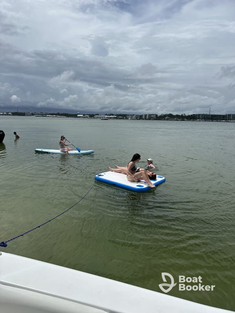 A group enjoys a fun day on the water, paddleboarding and relaxing on floating mats, perfect for summer adventures and water activities.