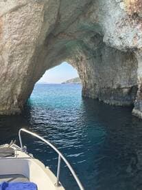 A stunning view of a boat entering a natural cave along the coastline, showcasing the beautiful turquoise waters and rocky formations — perfect for exploring scenic destinations.