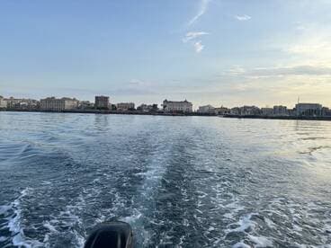 A serene view of the coastline from a boat, showcasing the beautiful harbor and cityscape — perfect for capturing the essence of a relaxing day on the water.