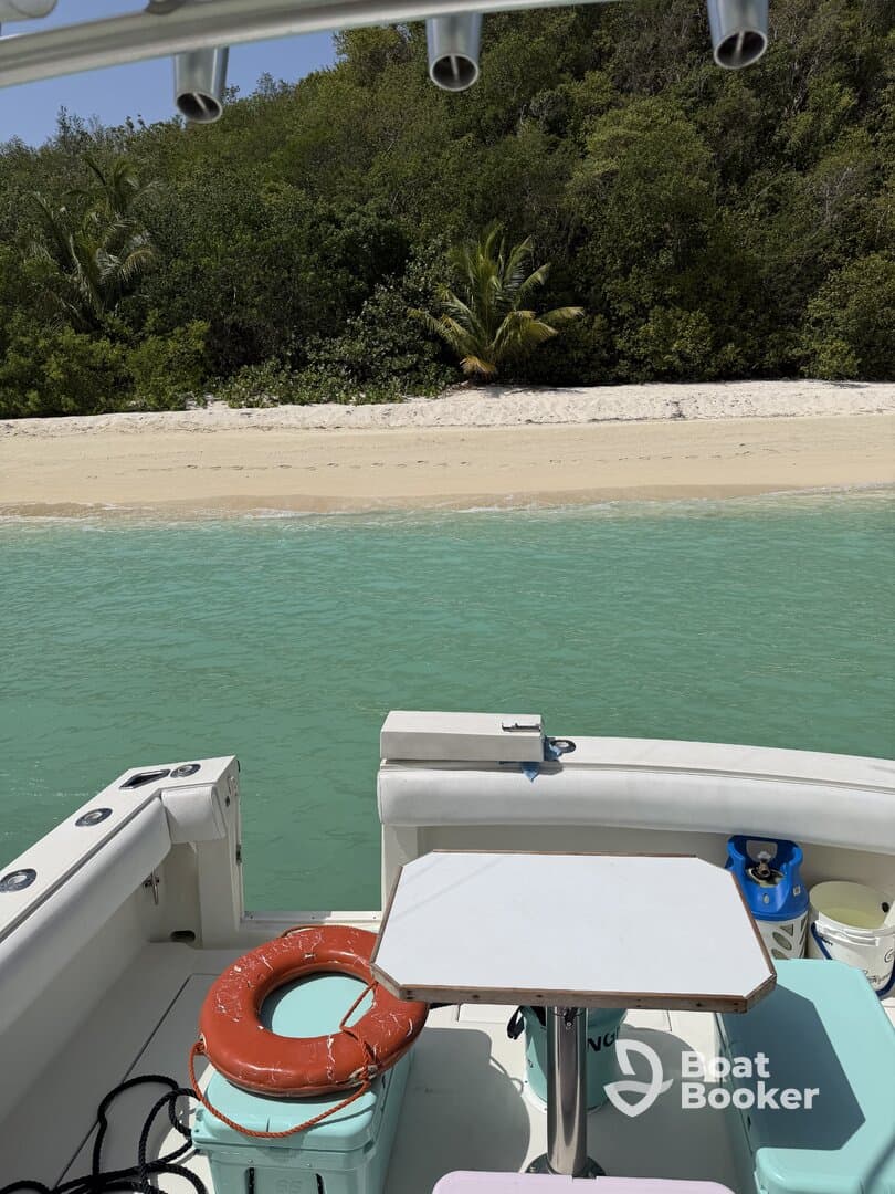 A view of the interior of a boat featuring a table and seating area, perfect for relaxing while enjoying the surrounding turquoise waters and sandy beach.