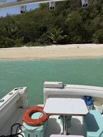 A view of the interior of a boat featuring a table and seating area, perfect for relaxing while enjoying the surrounding turquoise waters and sandy beach.
