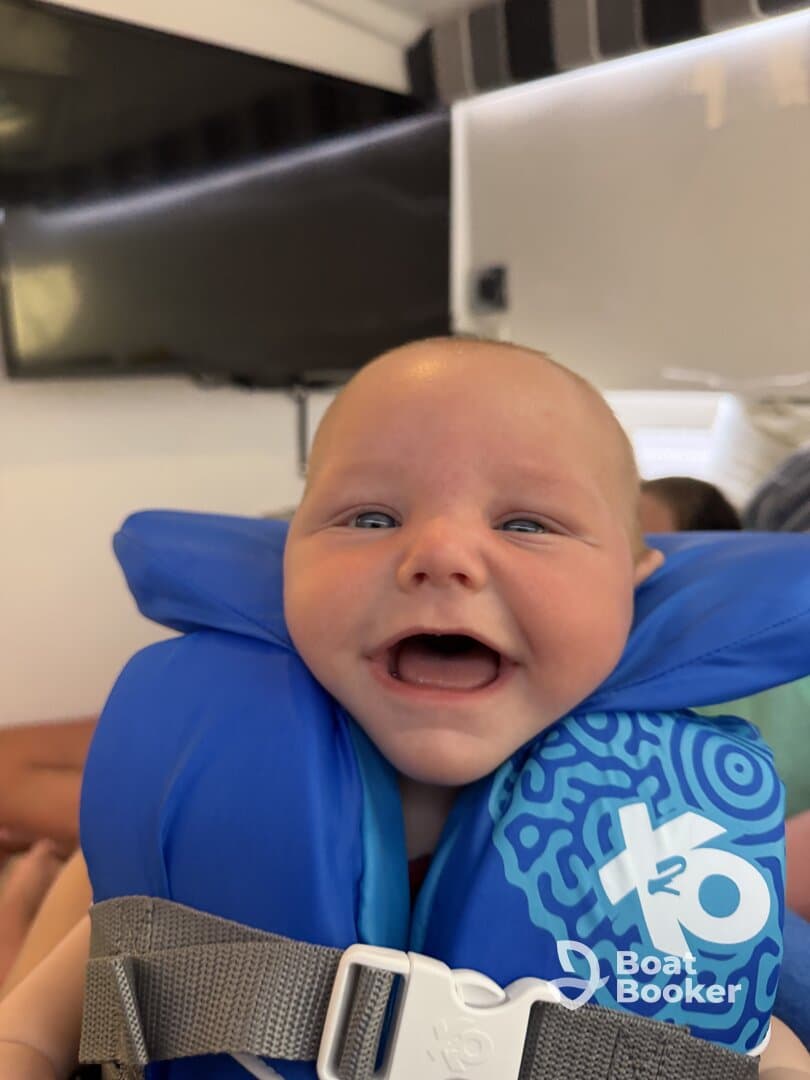 A joyful baby wearing a life jacket smiles brightly, capturing the excitement of a fun day on the water. Perfect for family boating adventures.