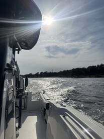 A scenic view from the side of a boat underway, capturing the sun's reflection on the water — perfect for showcasing boating adventures.