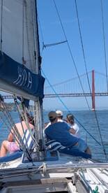A group enjoys a scenic sailing experience with a stunning view of the bridge in the background, perfect for memorable outings on the water.