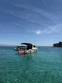A lively group enjoys a sunny day on a boat in crystal-clear waters, perfect for swimming and relaxation. Ideal for summer outings and family adventures.