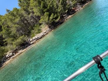 A stunning view of crystal-clear turquoise waters and a lush coastline, perfect for showcasing the beauty of a boating adventure.