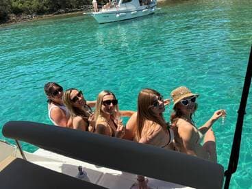 A group of friends enjoys a sunny day on the water, sipping cocktails and celebrating together — the perfect backdrop for a fun day out on the boat.