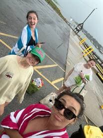 A cheerful group of friends poses for a fun selfie at the dock, capturing the excitement of their boating adventure despite the rainy weather.