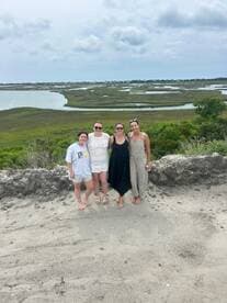 A group of friends poses together against a scenic backdrop of marshland, capturing a memorable moment during their outdoor adventure.