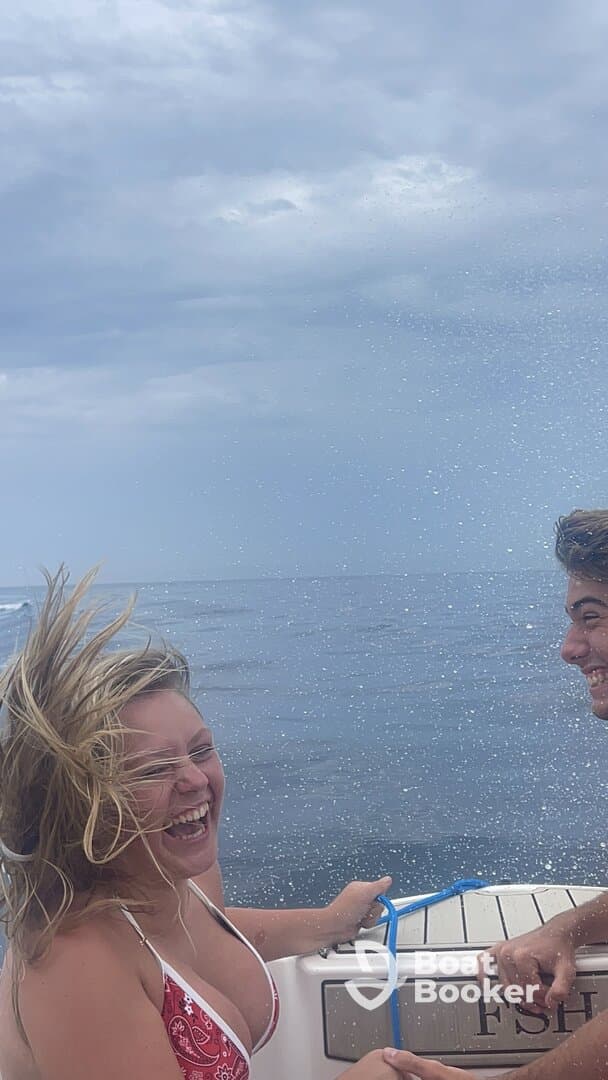 Two friends enjoy a thrilling moment on a boat, laughing and splashing in the water — a perfect snapshot of summer fun on the ocean.