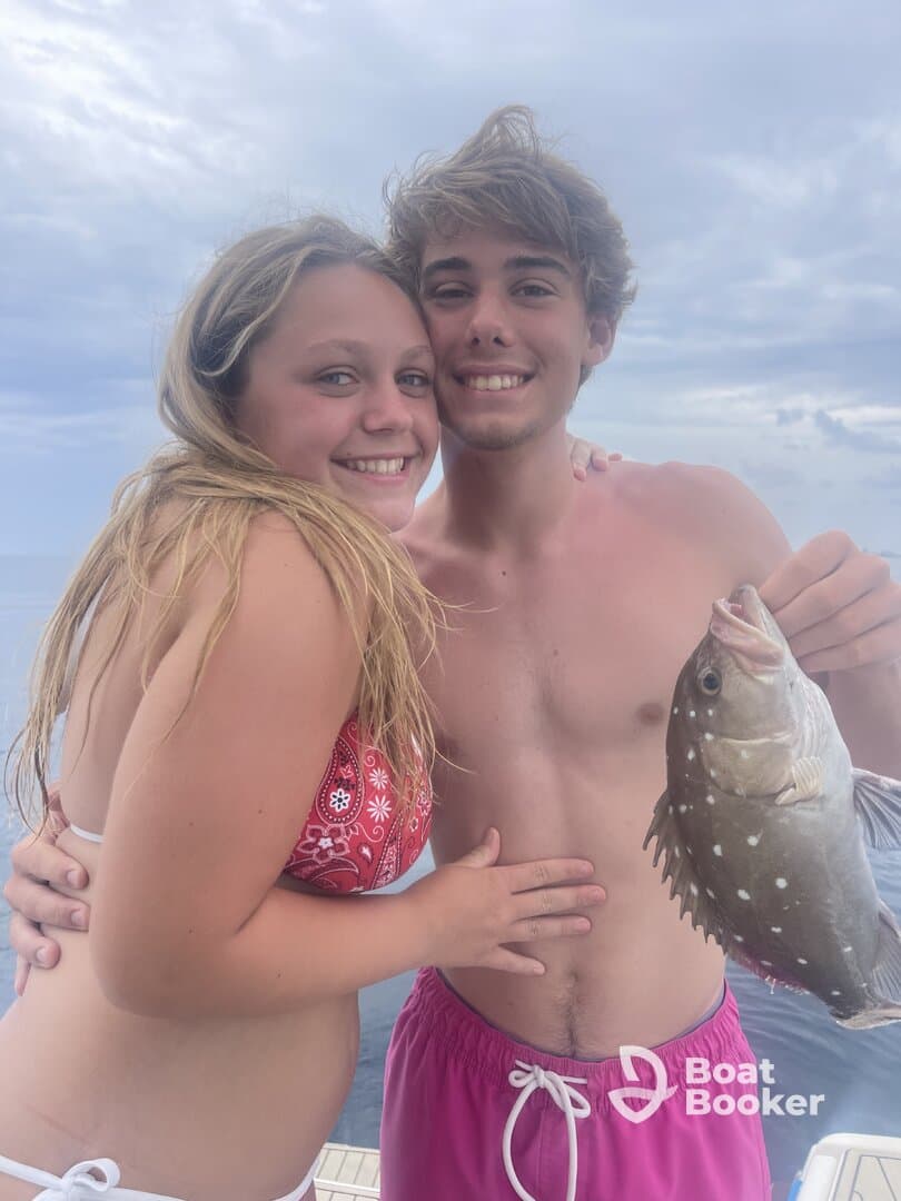 A joyful couple proudly displays their catch while enjoying a fishing trip at sea — a perfect moment of celebration and adventure on the water.