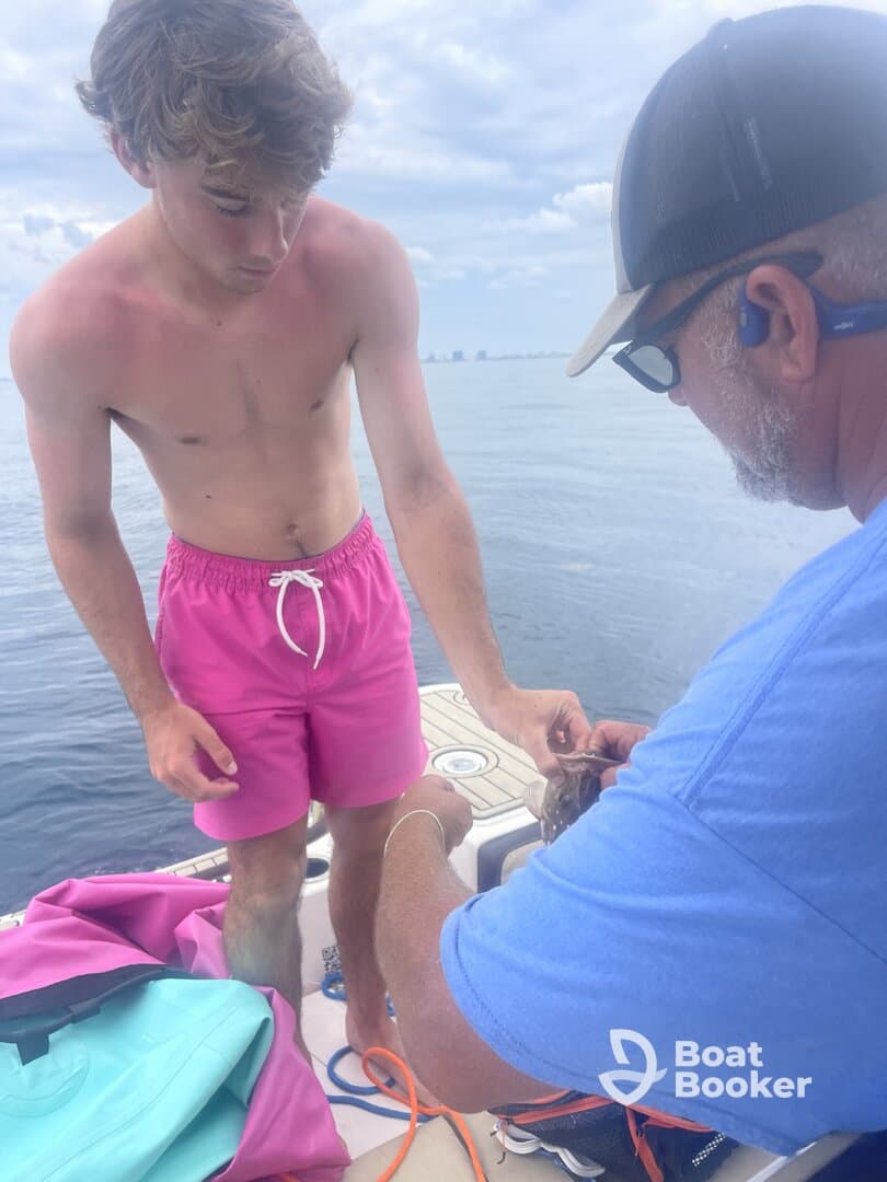 A young man and an adult engage in fishing on a boat, showcasing a memorable moment on the water. Perfect for fishing enthusiasts and family outings.