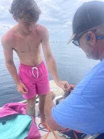 A young man and an adult engage in fishing on a boat, showcasing a memorable moment on the water. Perfect for fishing enthusiasts and family outings.