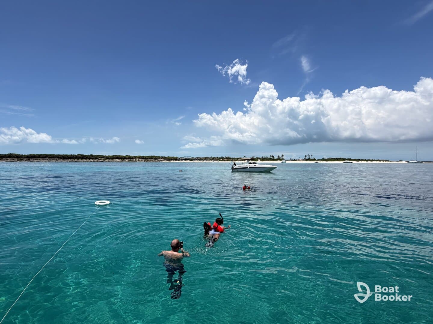 A group enjoys a fun day of snorkeling and swimming in crystal-clear waters, with a boat anchored nearby, perfect for a beach adventure.