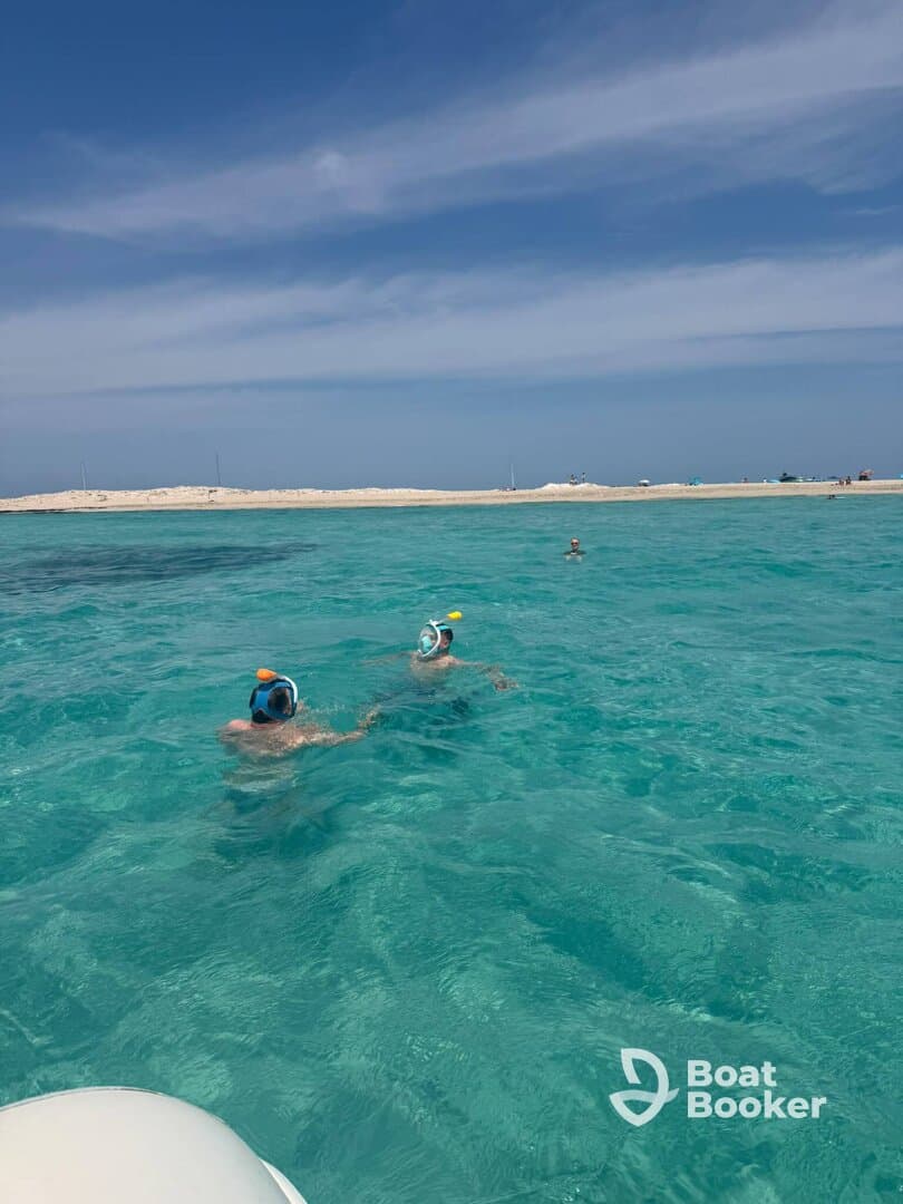 Two snorkelers explore the vibrant turquoise waters, enjoying a perfect day of swimming and adventure near a beautiful sandy beach.