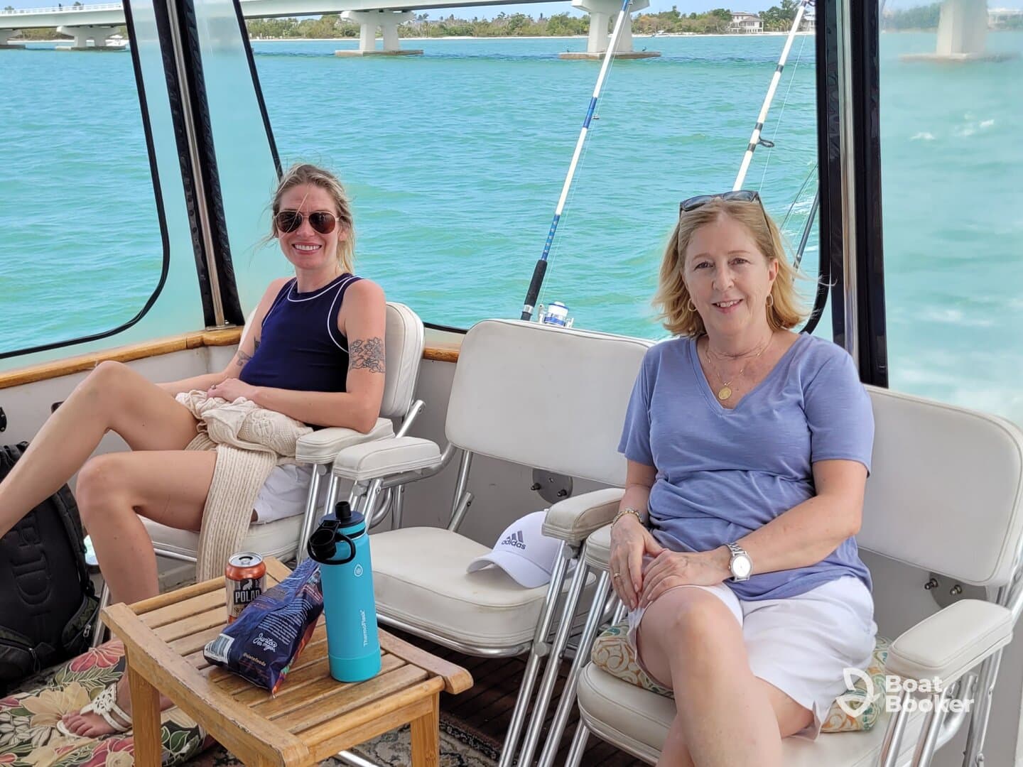 Two women relax in the cabin of a boat, enjoying the scenic views of the water. The comfortable seating and laid-back atmosphere make it an ideal spot for socializing on the water.