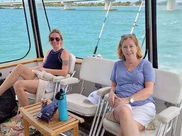 Two women relax in the cabin of a boat, enjoying the scenic views of the water. The comfortable seating and laid-back atmosphere make it an ideal spot for socializing on the water.