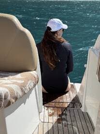 A woman enjoys a moment of relaxation on the deck of a boat, overlooking the sparkling water — a perfect scene for unwinding on a sunny day.