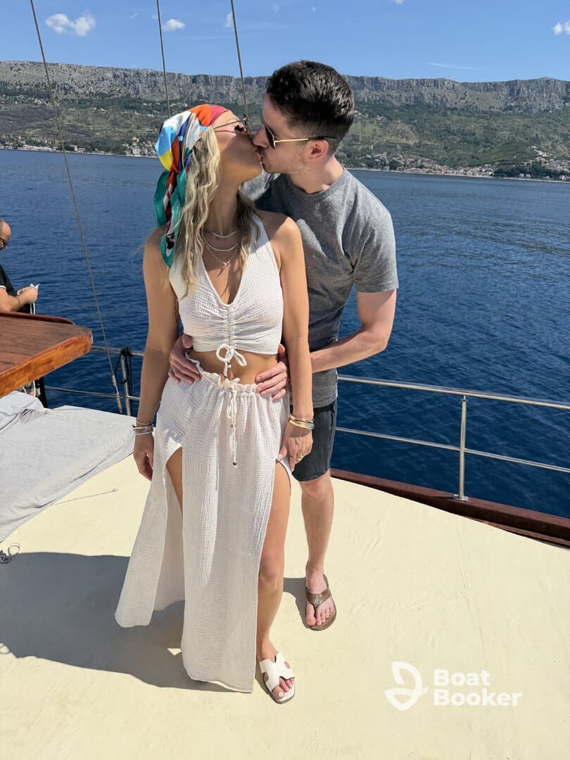A couple shares a romantic kiss aboard a yacht, surrounded by stunning coastal scenery — perfect for memorable moments on the water.