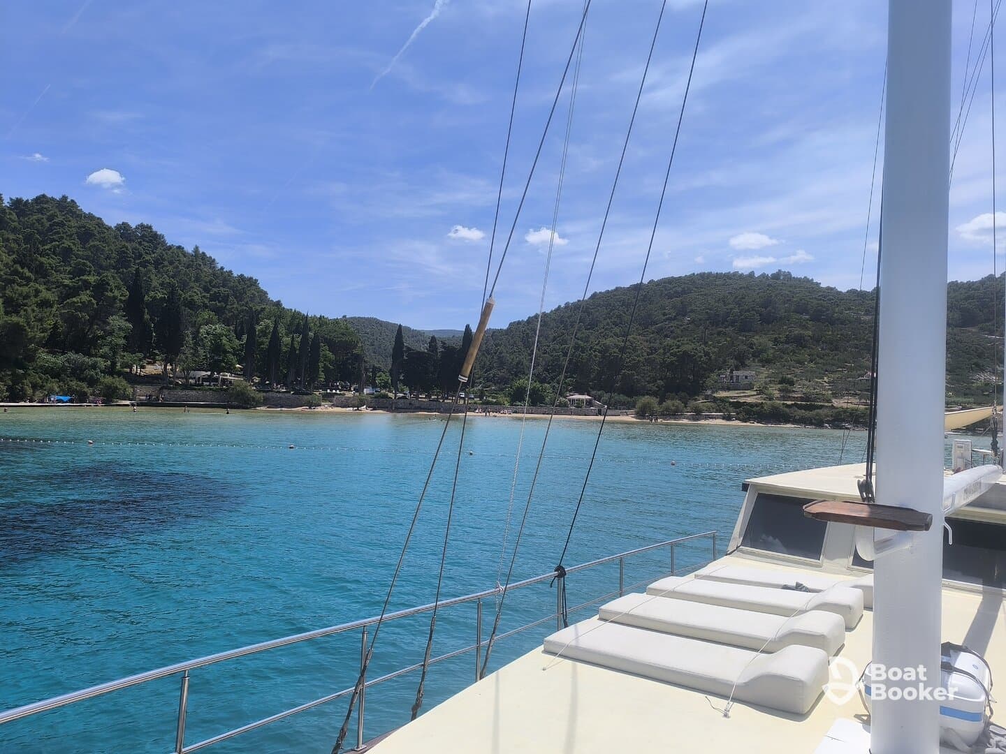 A serene view from the deck of a yacht, showcasing the turquoise waters and lush greenery of the coastline — perfect for a relaxing day on the water.