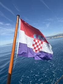 The Croatian flag waves proudly on a boat, set against a serene ocean backdrop — a symbol of maritime adventure in the beautiful Adriatic Sea.