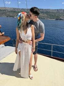 A couple shares a romantic kiss aboard a yacht, surrounded by stunning coastal scenery — perfect for memorable moments on the water.