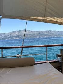 A serene view from the lounge area of a boat, showcasing the tranquil waters and distant mountains — perfect for relaxation and enjoying the scenery.