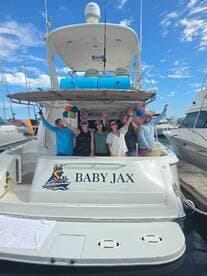 A lively group celebrates aboard the 'Baby Jax' yacht, showcasing a festive atmosphere with balloons and smiles — perfect for memorable gatherings on the water.