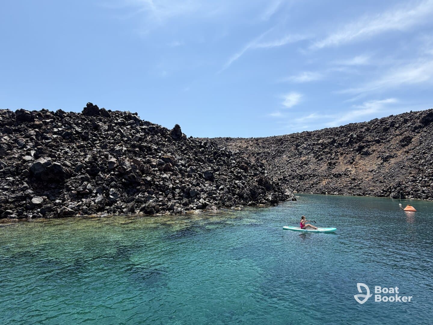 A young girl paddleboards in crystal-clear waters surrounded by a stunning rocky coastline, showcasing the beauty of outdoor adventures.